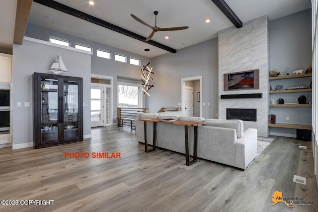 16074 Mountain Air Dr, Anchorage, AK 99516 - living room featuring beamed ceiling, a high ceiling, a large fireplace, a ceiling fan, and wood finished floors
