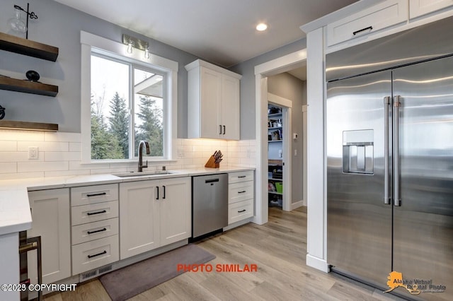 16074 Mountain Air Dr, Anchorage, AK 99516 - kitchen with stainless steel appliances, open shelves, a sink, white cabinetry, and light wood-type flooring