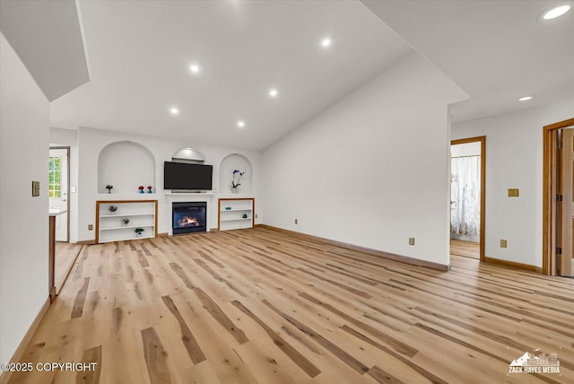11510 Tulin Park Loop, Anchorage, AK 99516 - unfurnished living room featuring light wood finished floors, recessed lighting, a glass covered fireplace, baseboards, and vaulted ceiling