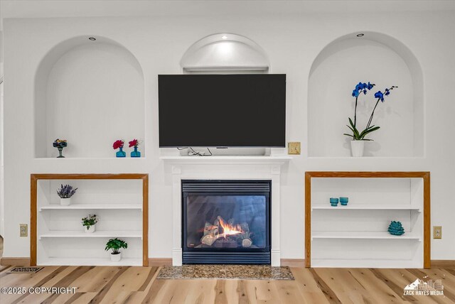 11510 Tulin Park Loop, Anchorage, AK 99516 - unfurnished living room with built in features, wood finished floors, a glass covered fireplace, and baseboards
