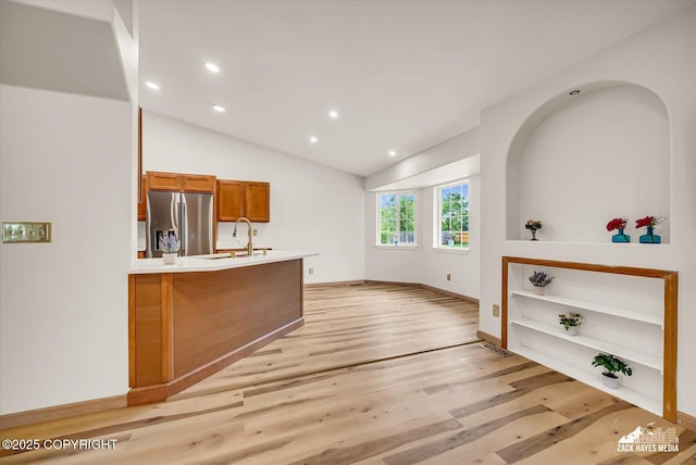 11510 Tulin Park Loop, Anchorage, AK 99516 - kitchen with stainless steel fridge with ice dispenser, brown cabinetry, recessed lighting, light wood-style flooring, and vaulted ceiling