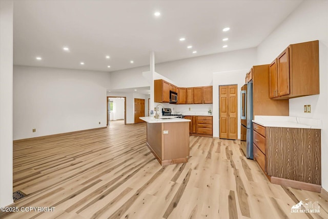 11510 Tulin Park Loop, Anchorage, AK 99516 - kitchen featuring appliances with stainless steel finishes, light countertops, brown cabinetry, a peninsula, and light wood finished floors