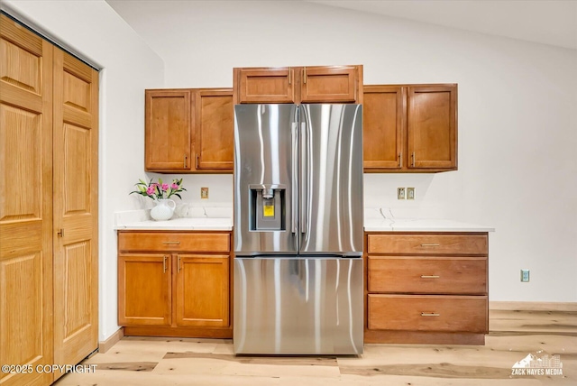 11510 Tulin Park Loop, Anchorage, AK 99516 - kitchen with stainless steel fridge, light wood-style floors, light countertops, brown cabinets, and lofted ceiling