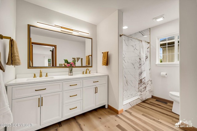 11510 Tulin Park Loop, Anchorage, AK 99516 - bathroom with double vanity, curtained shower, toilet, and wood finished floors