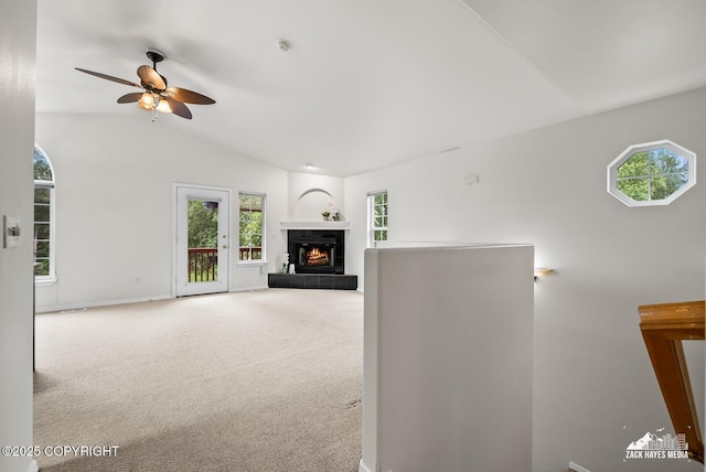 2578 Glacier St # 8, Anchorage, AK 99508 - unfurnished living room featuring lofted ceiling, ceiling fan, plenty of natural light, carpet flooring, and a tiled fireplace
