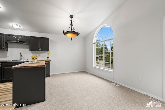2578 Glacier St # 8, Anchorage, AK 99508 - kitchen with wooden counters, dark cabinetry, light carpet, hanging light fixtures, and lofted ceiling