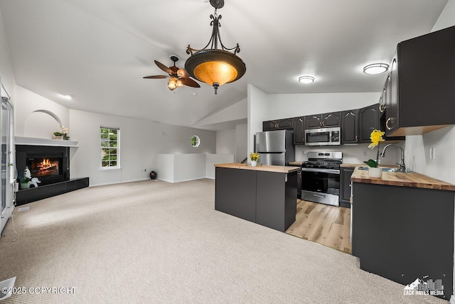 2578 Glacier St # 8, Anchorage, AK 99508 - kitchen featuring wood counters, appliances with stainless steel finishes, vaulted ceiling, ceiling fan, and light carpet