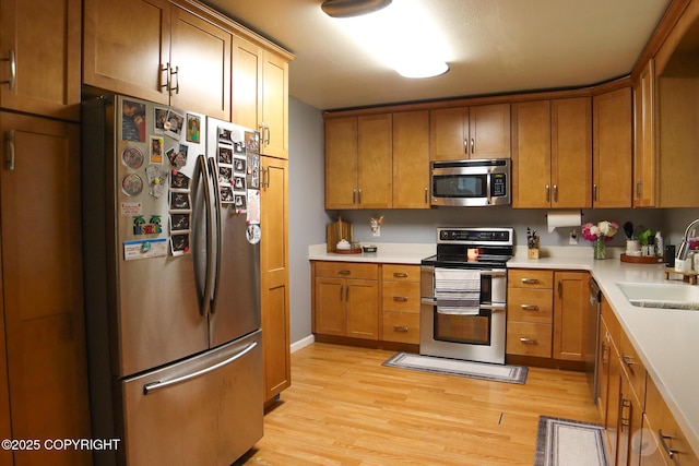 1468 Davison Rd, North Pole, AK 99705 - kitchen with a sink, brown cabinetry, light wood-style floors, stainless steel appliances, and light countertops