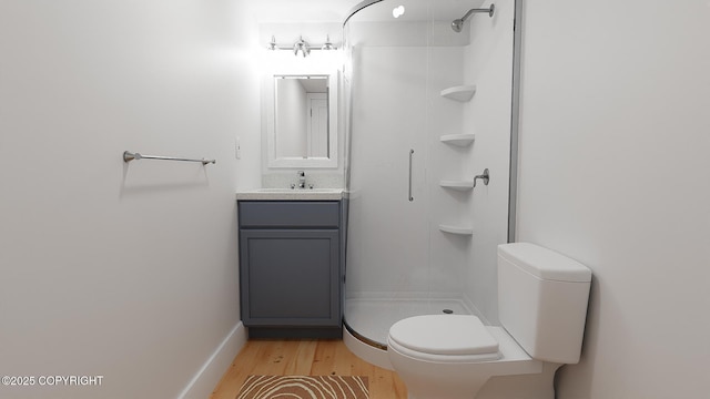 full bathroom with toilet, wood finished floors, a stall shower, vanity, and baseboards