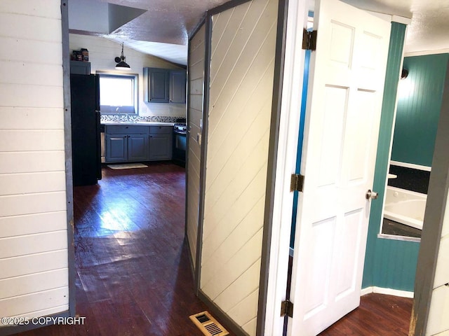 52899 Kingery Rd, Nikiski/North Kenai, AK 99611 - hallway with wood walls, dark wood-type flooring, visible vents, and vaulted ceiling