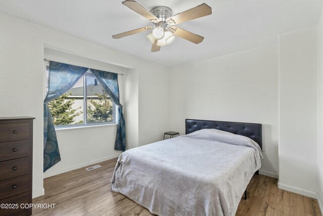 bedroom with visible vents, baseboards, ceiling fan, and wood finished floors