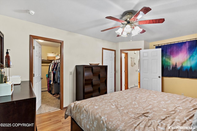 19111 Sarichef Loop, Eagle River, AK 99577 - bedroom featuring light wood-style flooring, baseboard heating, a ceiling fan, and a spacious closet