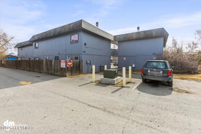exterior space with uncovered parking, fence, and mansard roof
