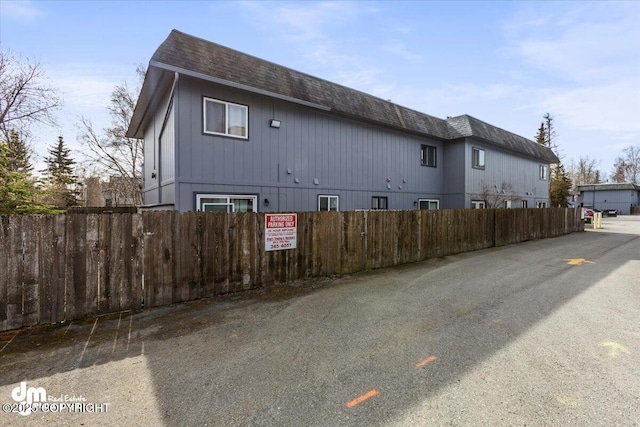 view of property exterior featuring fence, mansard roof, and roof with shingles