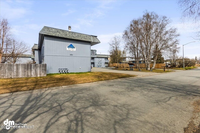 view of home's exterior featuring fence and a shingled roof