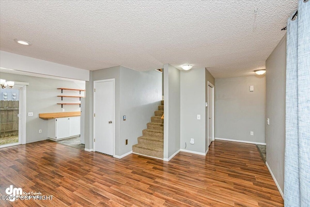 interior space featuring stairs, a textured ceiling, baseboards, and wood finished floors
