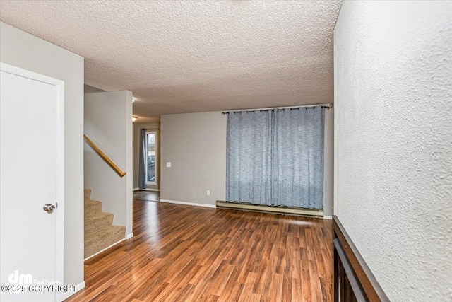 spare room with a textured ceiling, baseboards, stairs, and wood finished floors