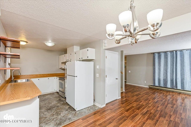 kitchen featuring an inviting chandelier, freestanding refrigerator, a textured ceiling, white cabinets, and a sink