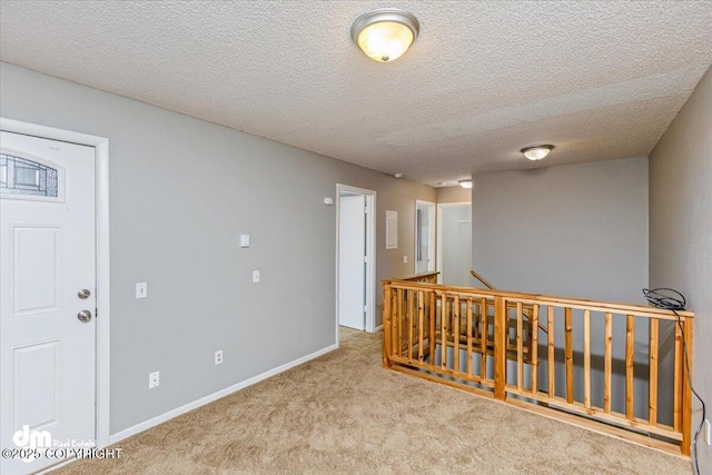 corridor with carpet flooring, a textured ceiling, an upstairs landing, and baseboards