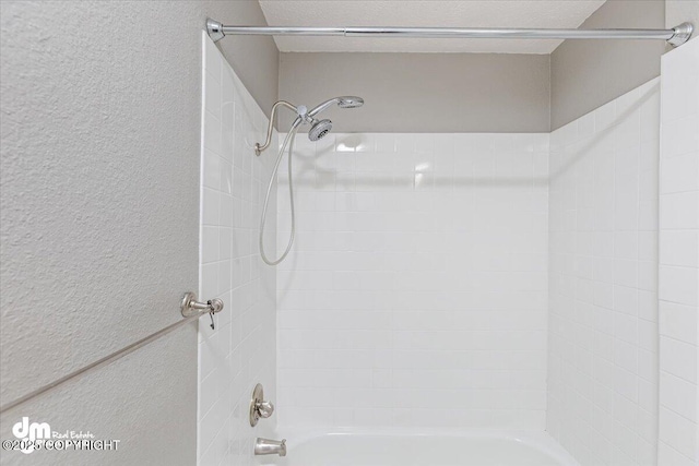 bathroom featuring shower / tub combination and a textured wall