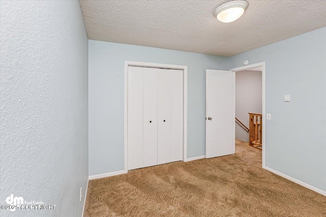 unfurnished bedroom with a textured ceiling, baseboards, carpet, and a closet