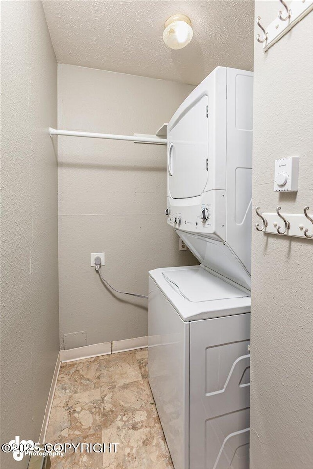 laundry room with baseboards, laundry area, stone finish flooring, and stacked washer / dryer