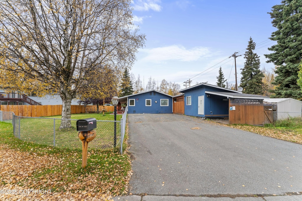 mid-century home with driveway, fence, and a front yard