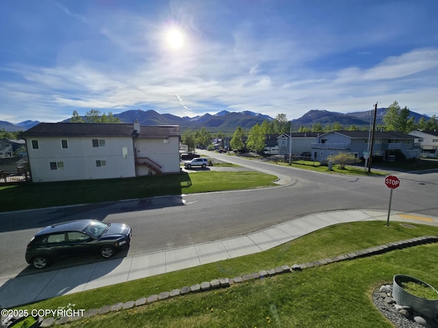 8041 Northwind Ave, Anchorage, AK 99504 - view of asphalt street featuring traffic signs, a mountain view, sidewalks, and a residential view