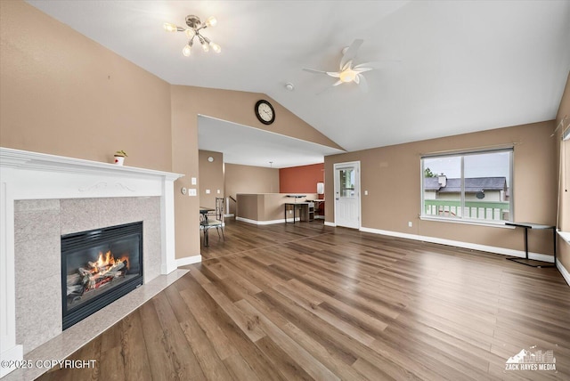 8041 Northwind Ave, Anchorage, AK 99504 - unfurnished living room with ceiling fan, a glass covered fireplace, lofted ceiling, wood finished floors, and baseboards