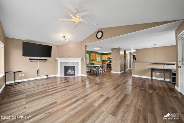 8041 Northwind Ave, Anchorage, AK 99504 - unfurnished living room featuring a ceiling fan, a tile fireplace, lofted ceiling, wood finished floors, and baseboards