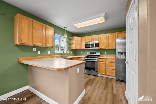 8041 Northwind Ave, Anchorage, AK 99504 - kitchen with appliances with stainless steel finishes, a peninsula, light wood-style flooring, light countertops, and baseboards