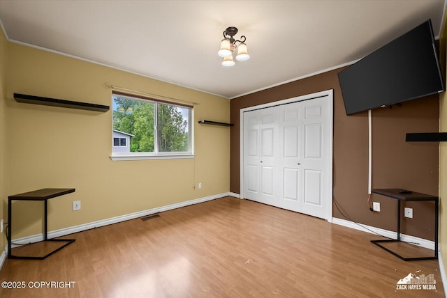 8041 Northwind Ave, Anchorage, AK 99504 - unfurnished bedroom featuring wood finished floors, baseboards, a chandelier, a closet, and crown molding