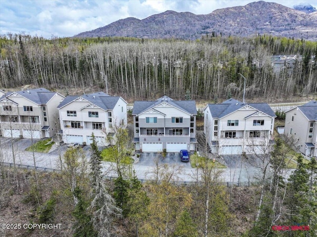 aerial view of residential area featuring a mountainous background and a heavily wooded area