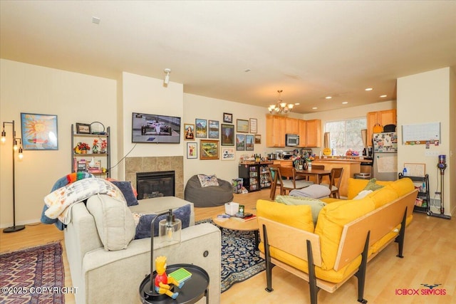 living room with a chandelier, light wood finished floors, a fireplace, and recessed lighting