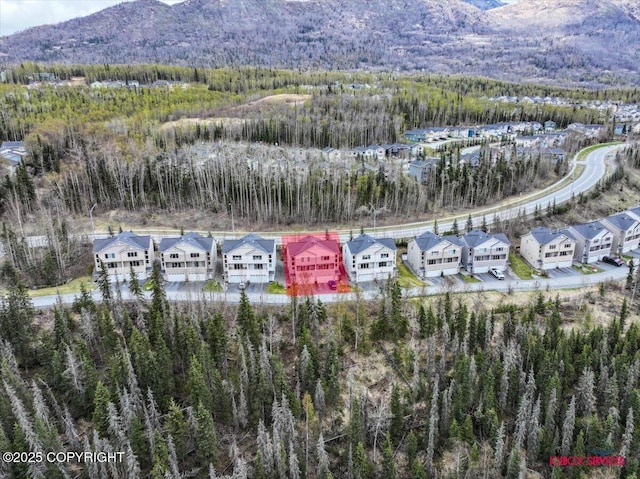 aerial view of residential area featuring a forest and a mountainous background