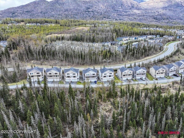 aerial overview of property's location featuring a heavily wooded area, a mountainous background, and nearby suburban area
