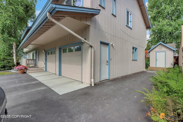 view of home's exterior with a storage shed, an outbuilding, and aphalt driveway