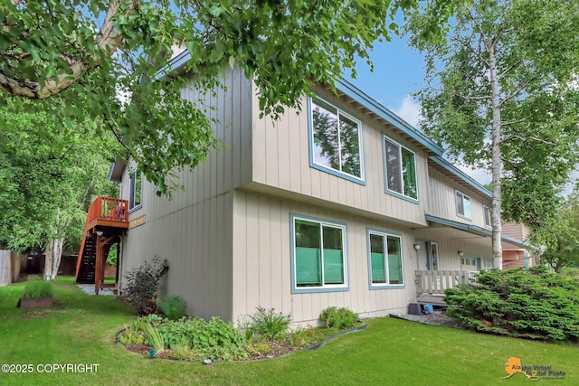 view of property exterior with a lawn, a wooden deck, and stairs