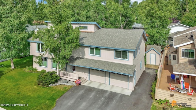 view of front facade featuring a shingled roof, an attached garage, a front yard, and aphalt driveway