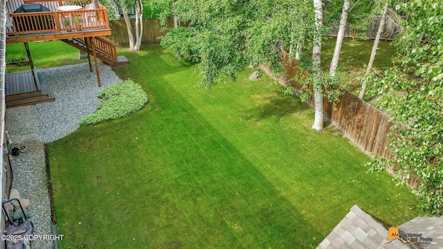 view of yard with a fenced backyard, a wooden deck, and stairway