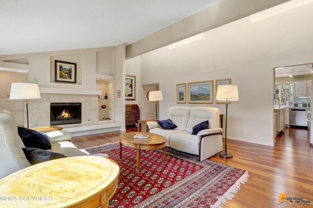 living area with wood-type flooring, a premium fireplace, baseboards, and built in features
