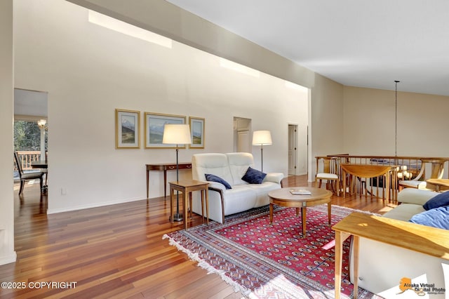 living room with an inviting chandelier, a towering ceiling, and hardwood / wood-style floors
