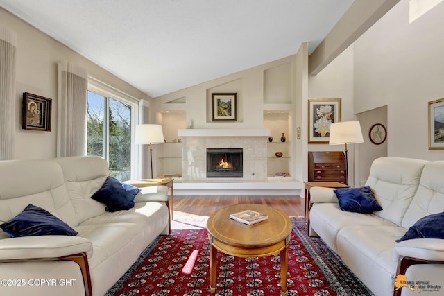 living area featuring wood finished floors, vaulted ceiling, and a tile fireplace