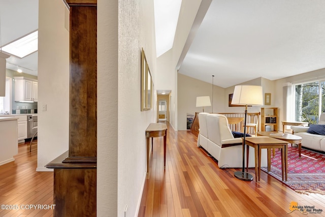 living room with vaulted ceiling with skylight and light wood finished floors