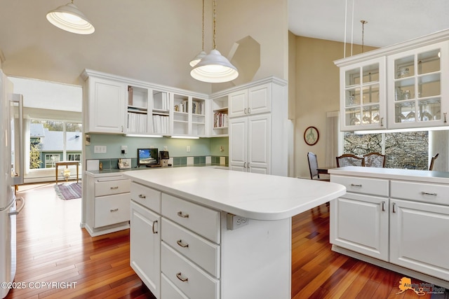 kitchen with open shelves, wood finished floors, high vaulted ceiling, glass insert cabinets, and white cabinetry