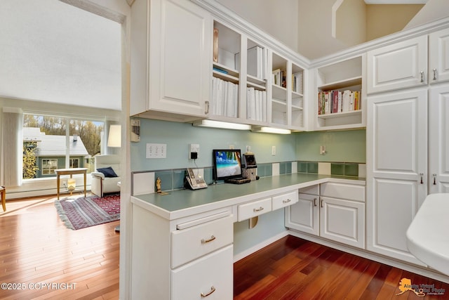 office featuring a baseboard radiator, built in desk, and dark wood-style floors