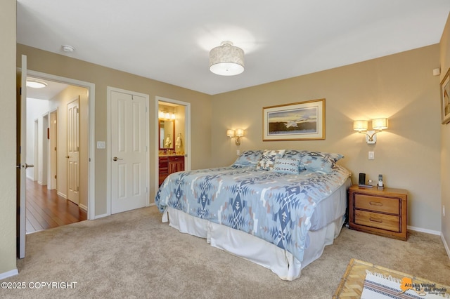 carpeted bedroom with baseboards and connected bathroom