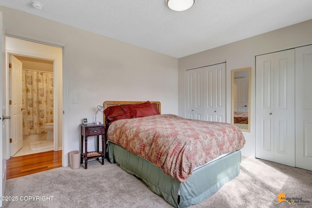 carpeted bedroom featuring two closets and a textured ceiling