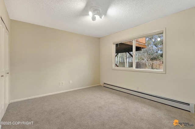 carpeted spare room with baseboards, a baseboard heating unit, and a textured ceiling