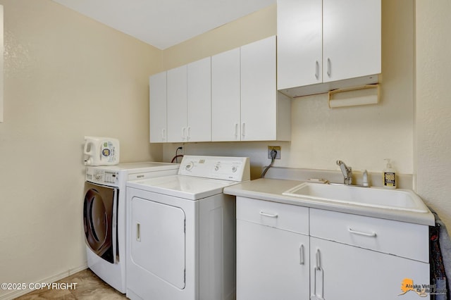 laundry room featuring a sink, baseboards, cabinet space, and washer and clothes dryer
